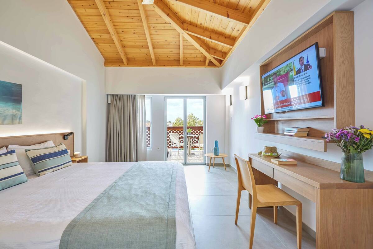 Een moderne hotelkamer met een bed, bureau, televisie en een balkon.