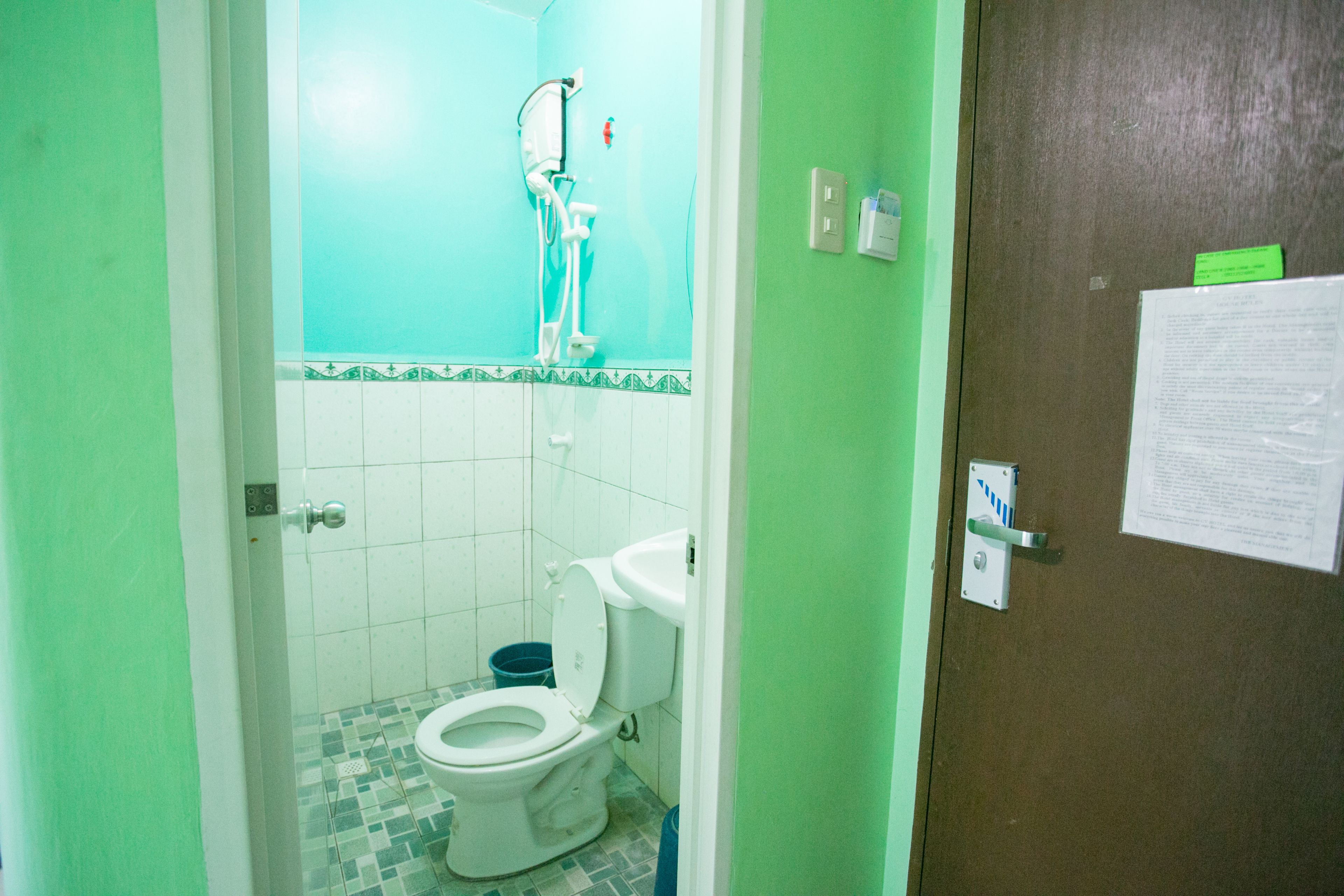 Een badkamer met een toilet, douche en betegelde vloer.
