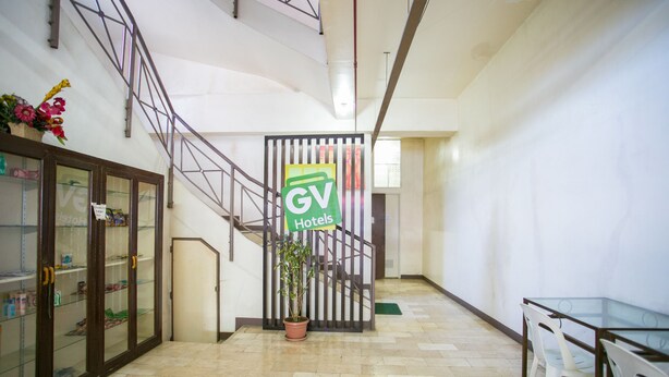 Un hall de hotel con una escalera, una recepción y una planta en maceta.