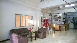 Un vestíbulo amplio con una recepción, dos sofás, una mesa de centro y una escalera al fondo.
