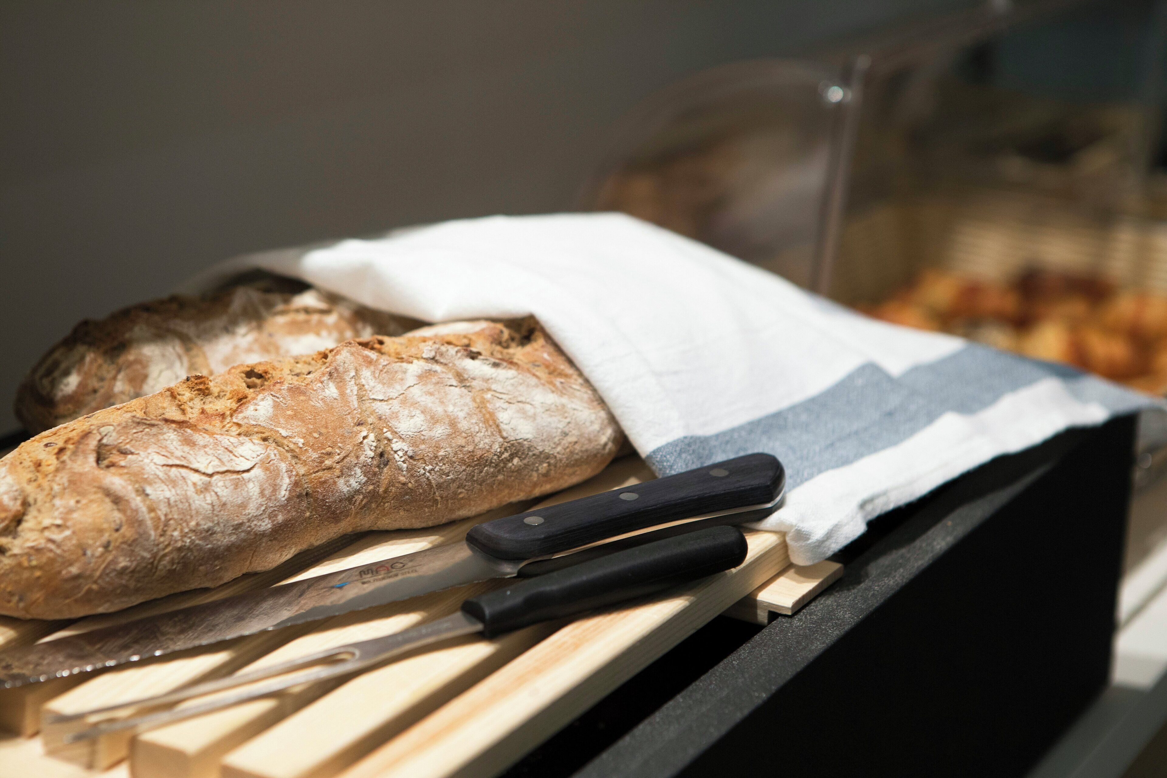 A loaf of bread on a wooden surface with a knife and a cloth.