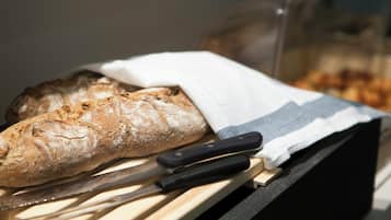 A loaf of bread on a wooden surface with a knife and a cloth.