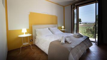 Habitación de hotel con una cama, una mesita de noche con lámpara y vistas al exterior.