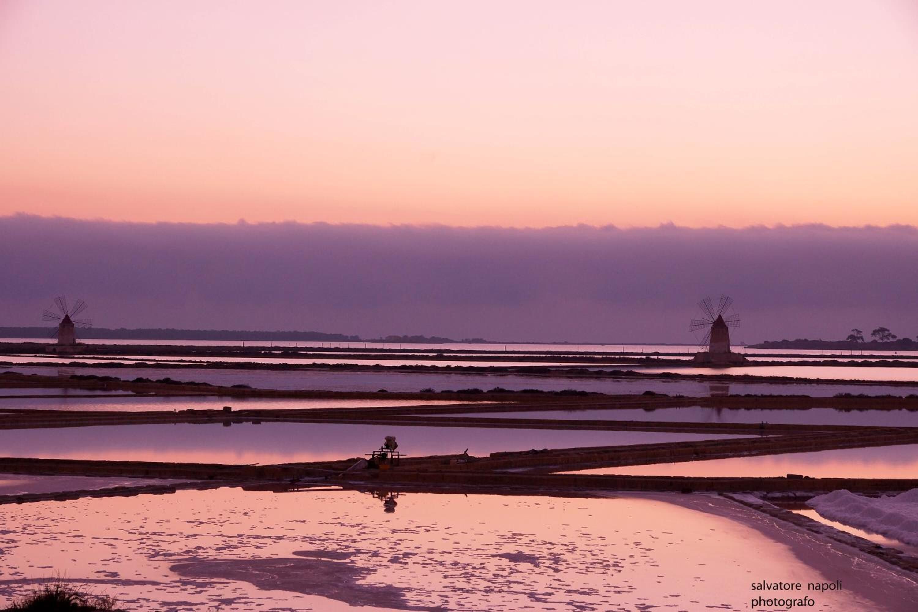 A serene landscape with windmills and reflective water bodies, likely a tourist attraction.