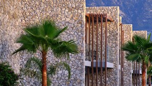 Un resort con paredes de piedra, palmeras y sillas de descanso.