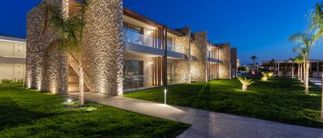 A modern house with stone facades, a well-maintained lawn, and outdoor seating.