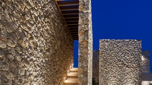 Un edificio revestido de piedra con una escalera que conduce a una zona cubierta.