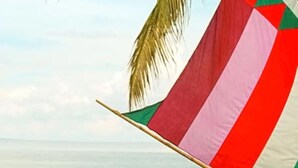 A flag with horizontal stripes of red, white, and green, set against a backdrop of a calm sea and a clear sky. - GV Hotel Ipil (Ipil)