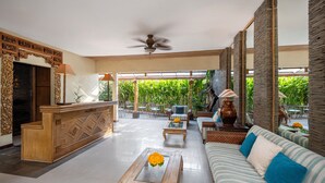 A spacious lobby with a reception desk, sofas, and a ceiling fan. - Pondok Sari (Kuta)