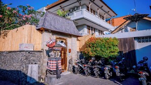 A traditional house with a tiled roof, a stone wall, and a wooden fence. - Pondok Sari (Kuta)