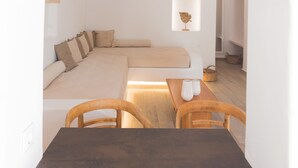 A minimalist living space with a sofa, dining table, and arched doorway. - Akti Kastraki Beach (Naxos)