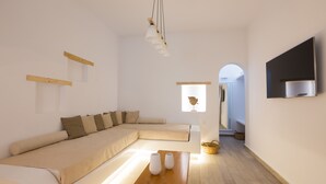 A modern living room with a sectional sofa, a wooden coffee table, and a flat-screen TV mounted on the wall. - Akti Kastraki Beach (Naxos)