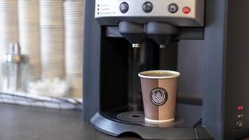 A coffee machine with a cup of coffee on its drip tray.
