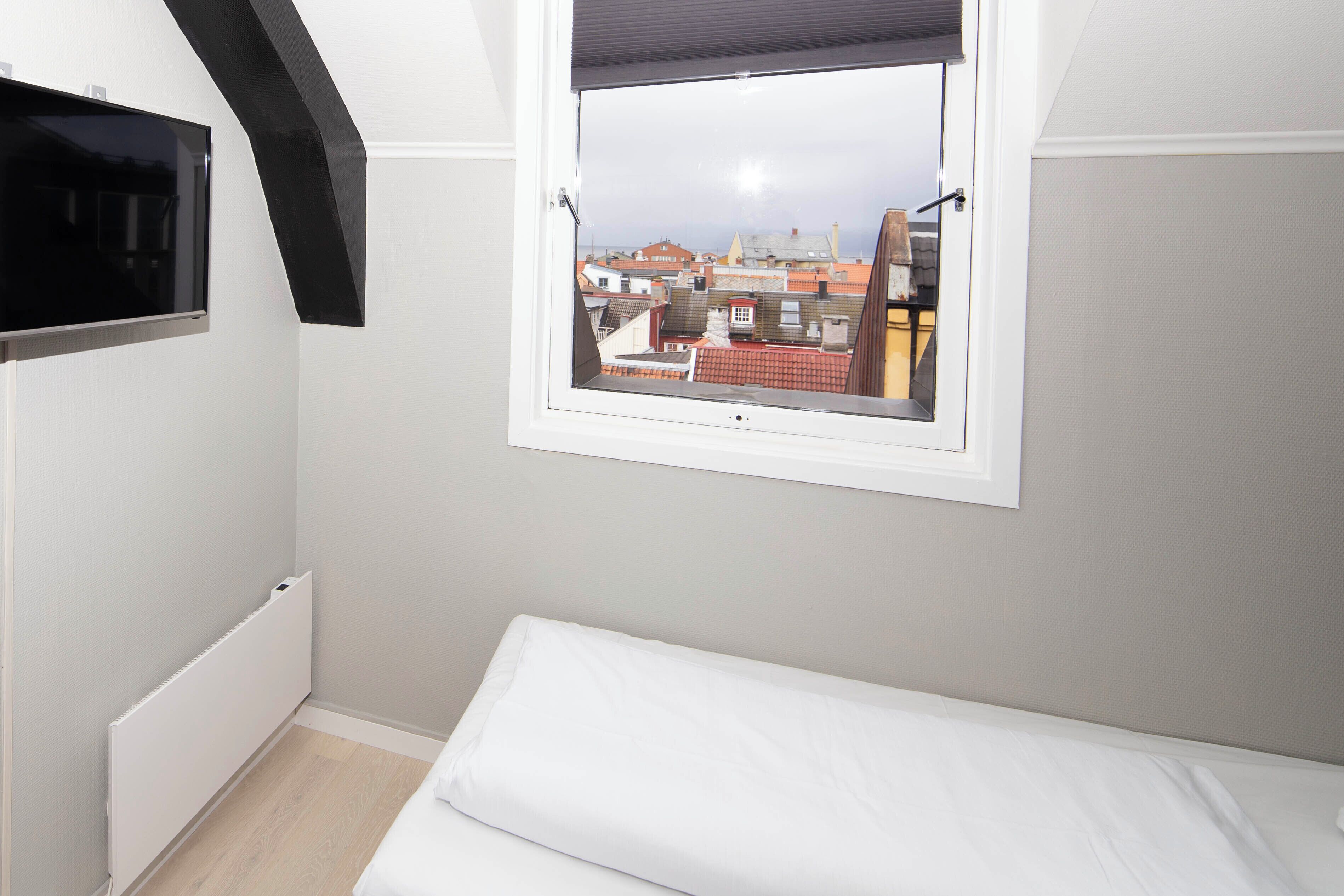 A bedroom with a window, a radiator, and a bed.