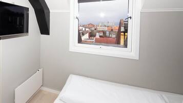 A bedroom with a window, a radiator, and a bed.