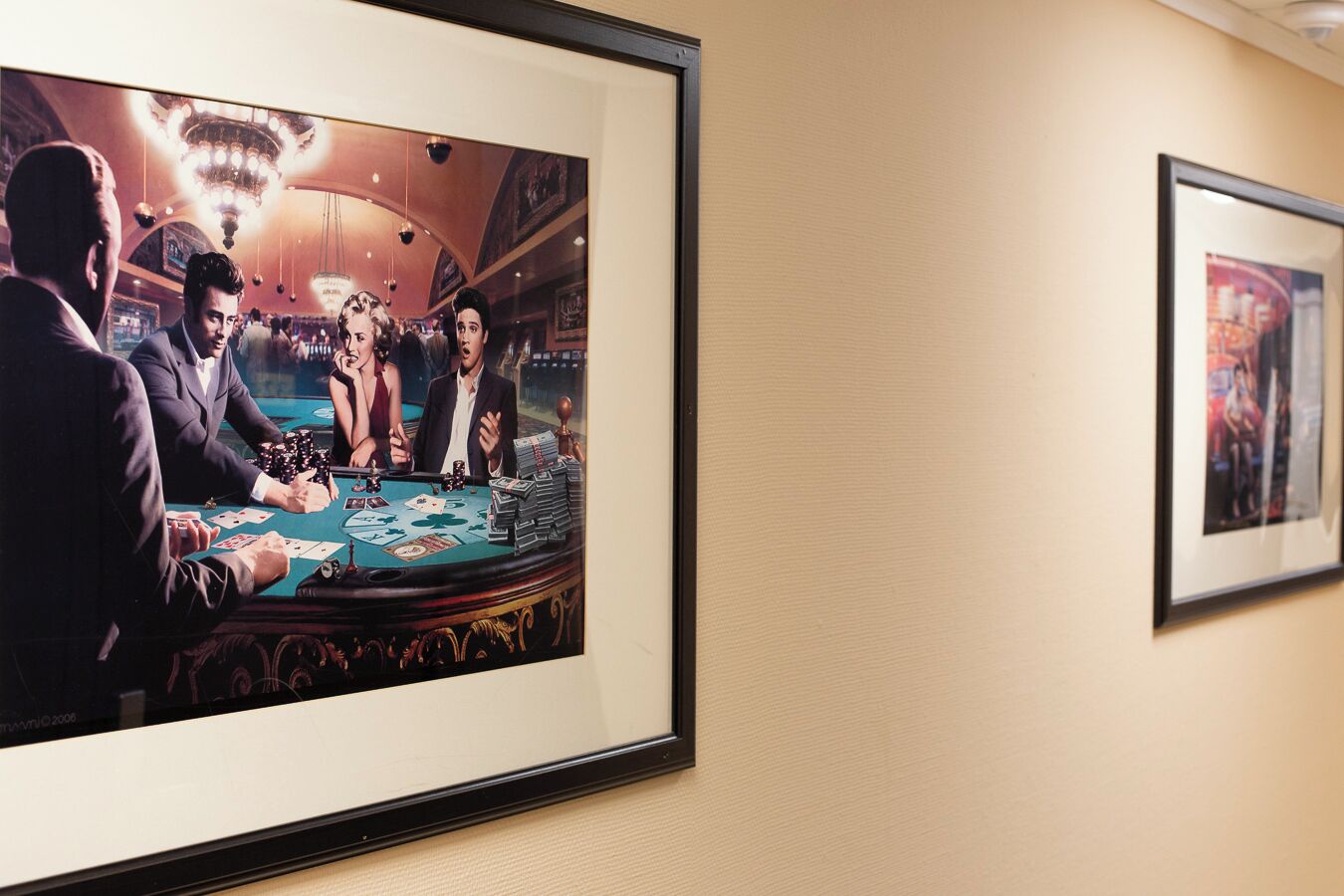 A framed photograph of a casino scene with a blackjack table, players, and a chandelier.