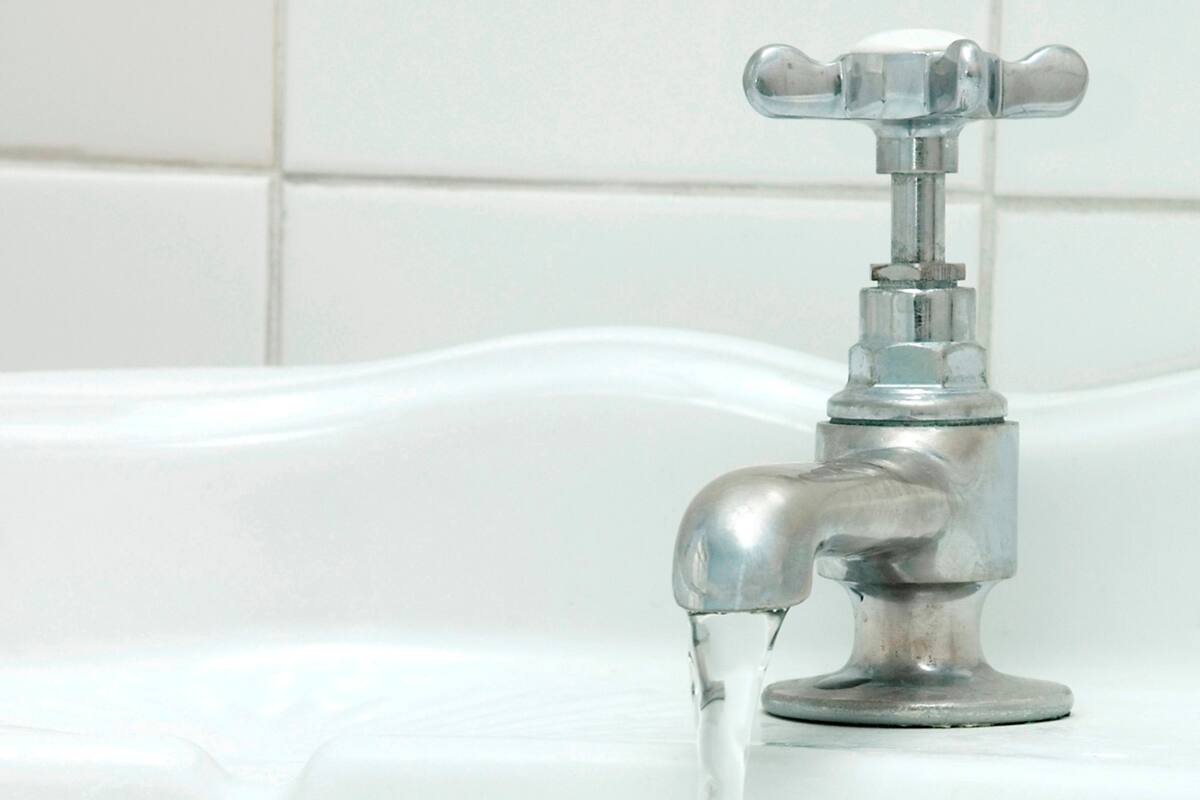 Une salle de bain avec un robinet chromé et un mur recouvert de carreaux blancs.
