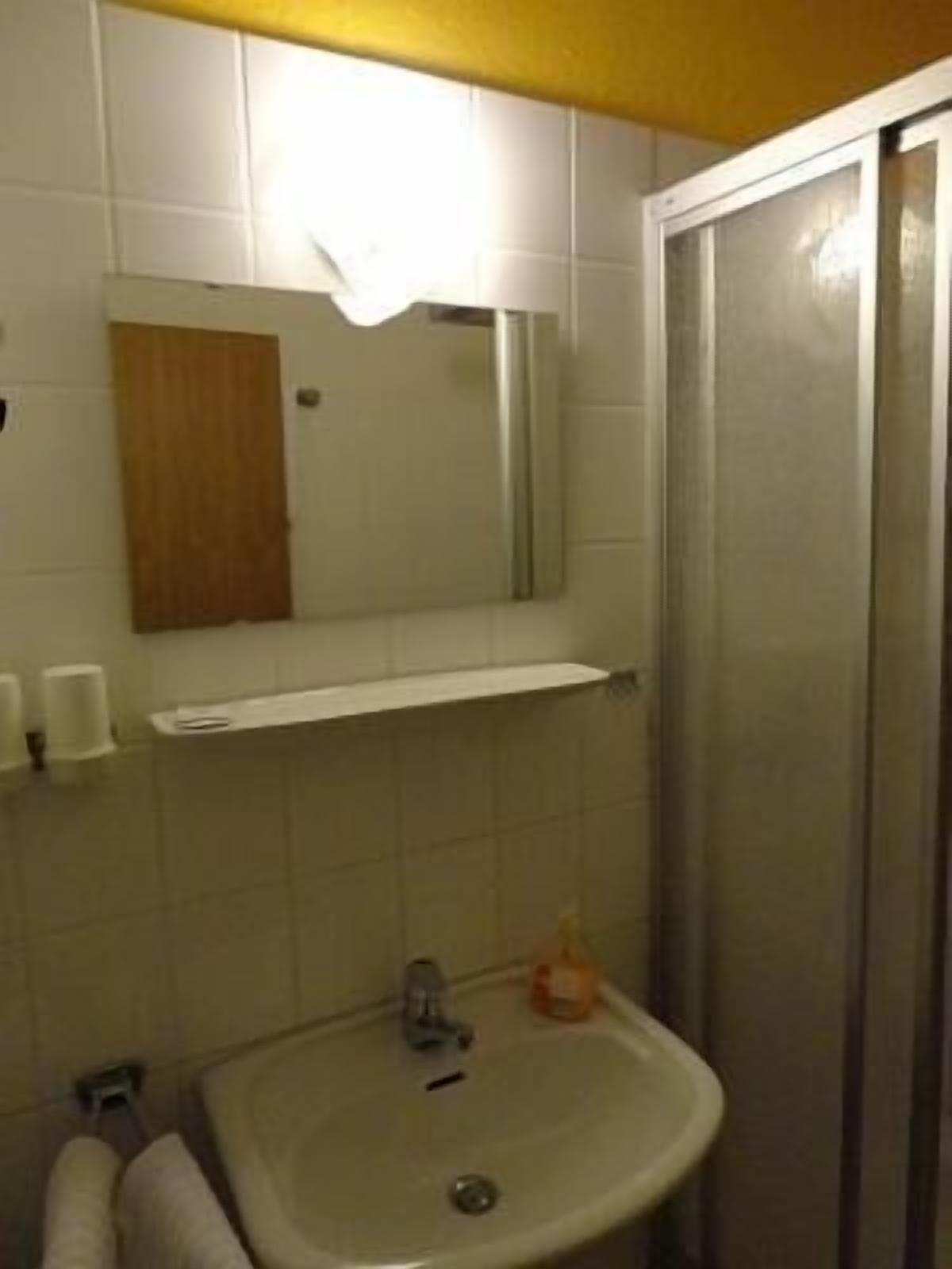 A bathroom with a sink, mirror, and shower.