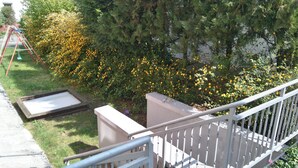 A balcony with a view of a garden with yellow flowers and a metal ladder. - Hotel Arheilger Hof (Darmstadt)