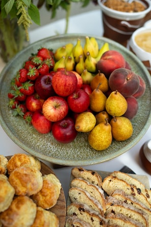 A fruit platter with apples, pears, and peaches, and a wooden board with sliced bread.
