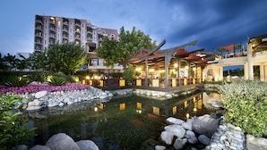 A hotel with a pond, outdoor seating, and a building with multiple floors and balconies. - Limak Limra Hotel & Resort  (Kemer)