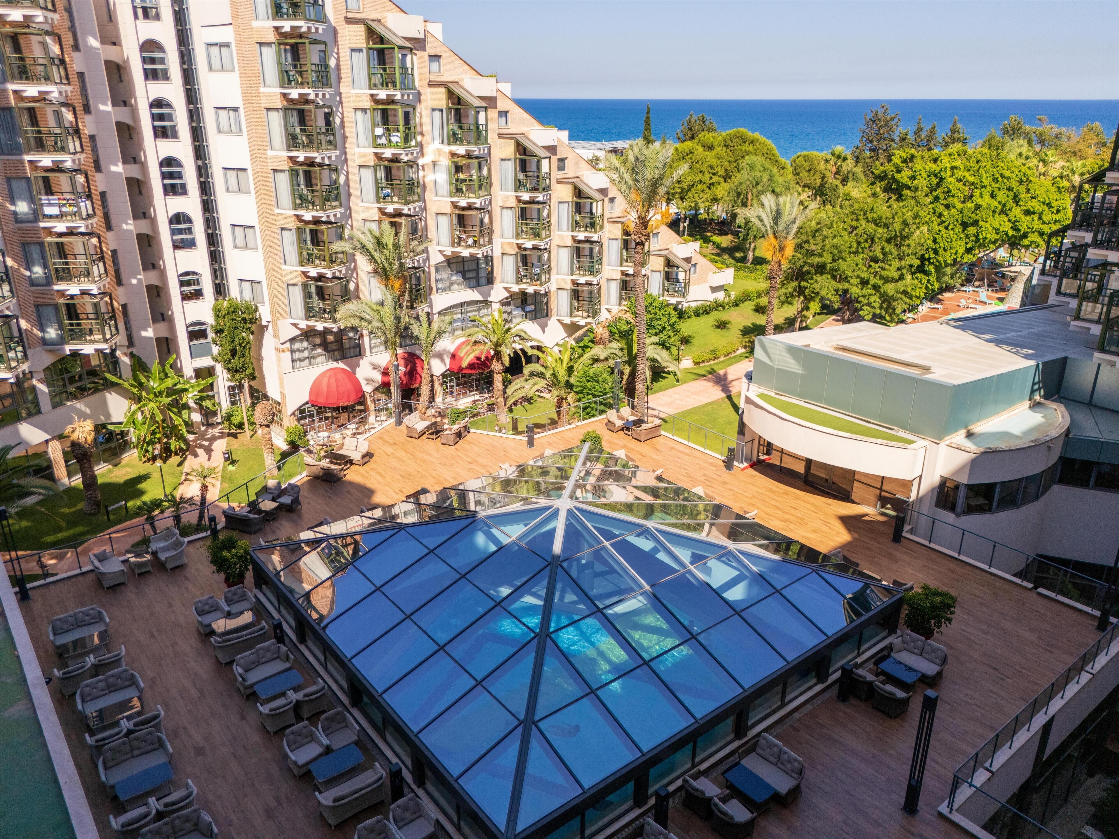 Ein Hochhotel mit Poolbereich auf dem Dach, Außenbereich zum Sitzen und Blick aufs Meer.
