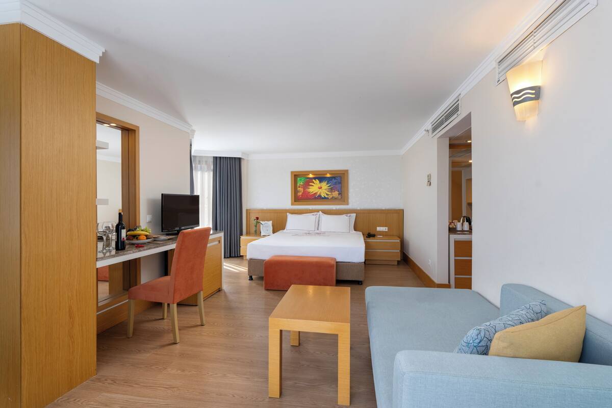 A hotel room with a bed, a desk with a chair, a sofa, and a small table.