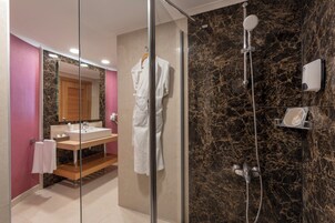 Een moderne badkamer met een douchecabine van glas, een wastafel met spiegel en een marmeren wand.