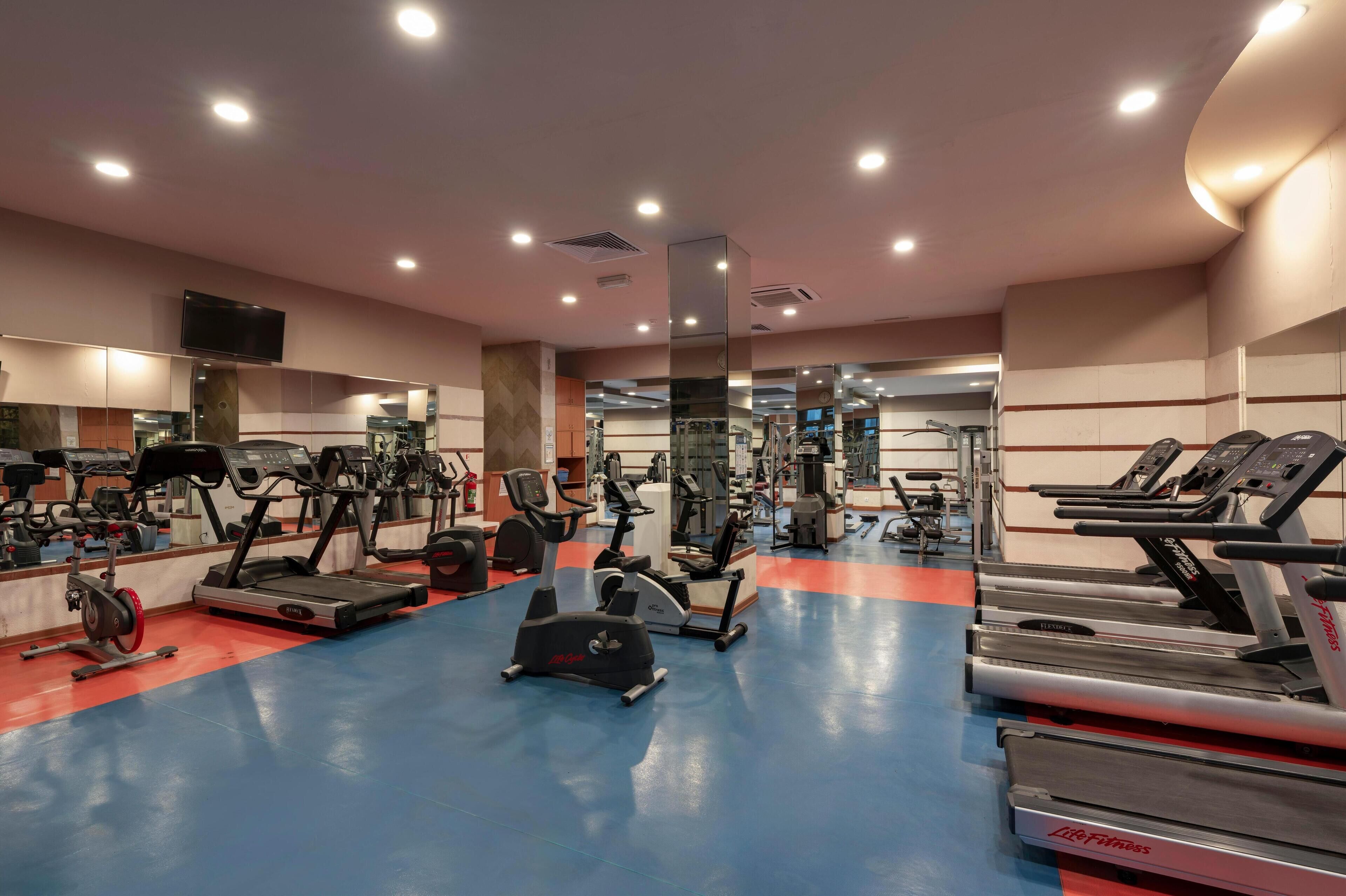 Uma academia com esteiras, elípticos e equipamentos de musculação.