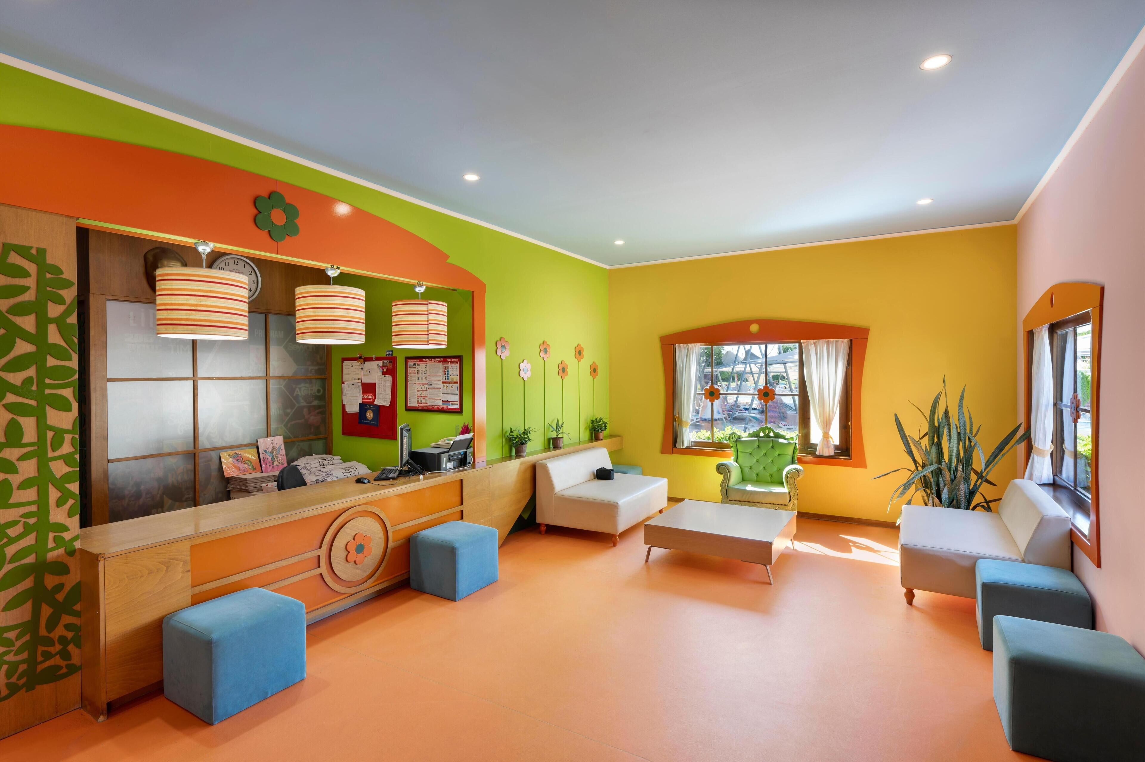 A brightly colored room with a reception desk, seating area, and large windows.