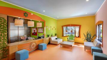 A brightly colored room with a reception desk, seating area, and large windows.