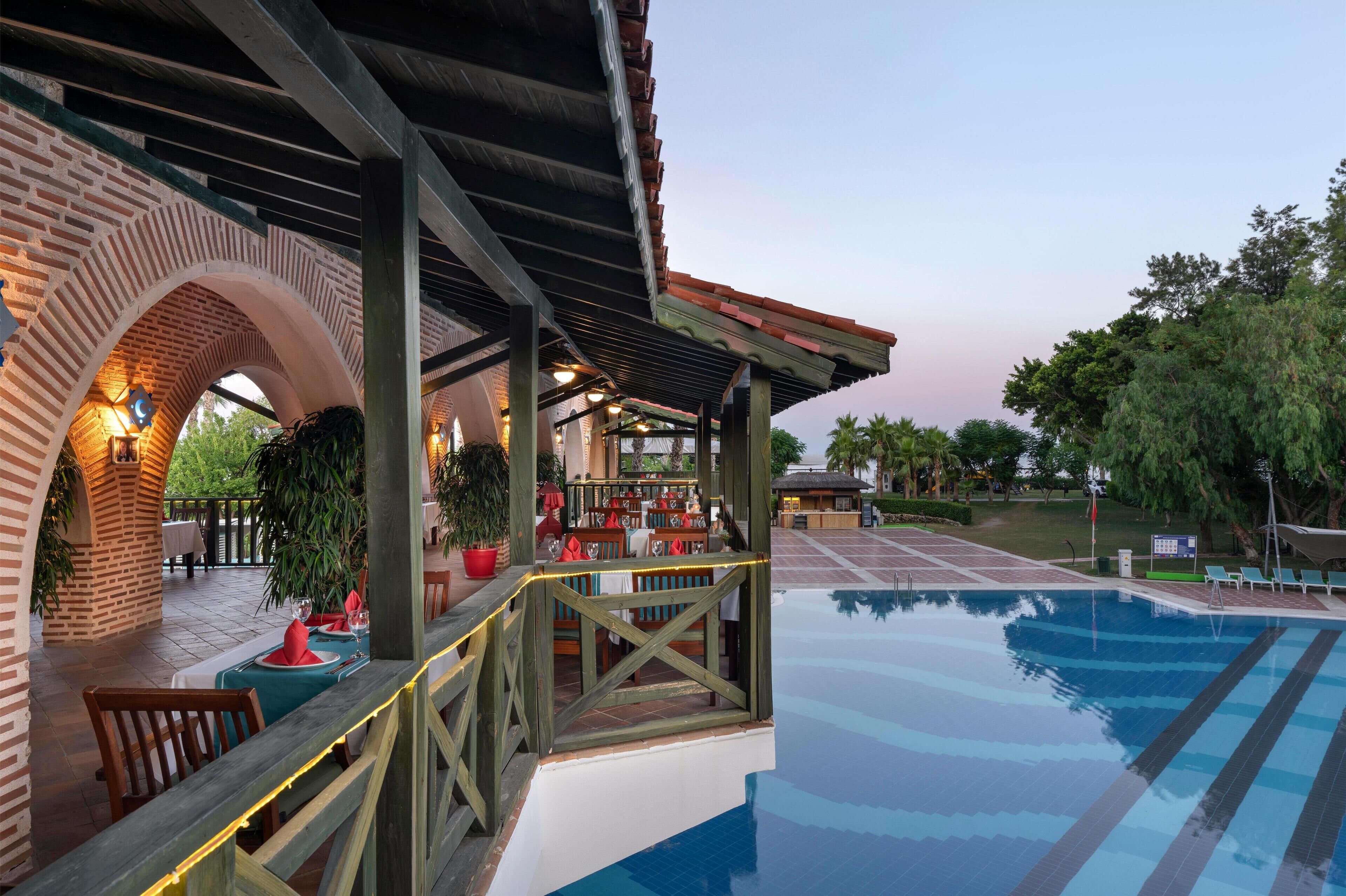 Un área de piscina al aire libre con una zona de estar techada y una estructura de ladrillo.