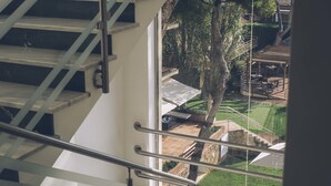 Una escalera con barandas de metal que lleva a un espacio exterior con césped y una estructura de piedra.