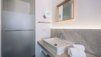 A modern bathroom with a large sink, a mirror with a light, and a towel on the counter.