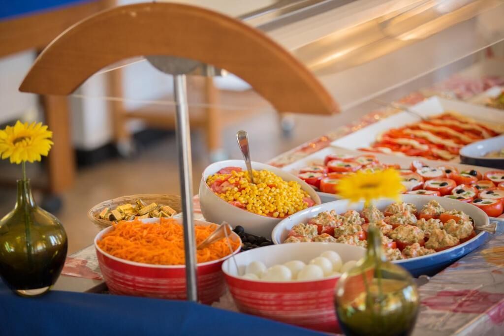 Un bufé con diversos platos, incluyendo ensaladas, pasta y otras preparaciones culinarias.