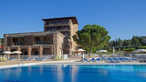 Un hotel con piscina, sillones de descanso y sombrillas.