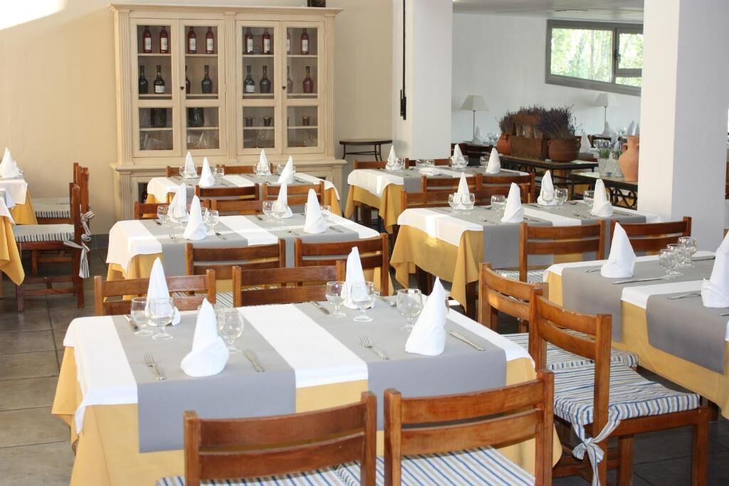 Un restaurant où de nombreuses tables sont dressées pour le service, chacune étant recouverte d’une nappe blanche et agrémentée de serviettes.