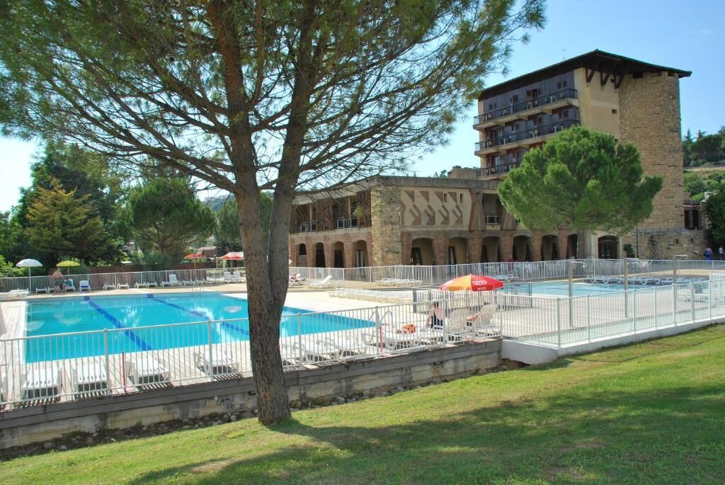 A hotel with a swimming pool, outdoor seating, and a building with multiple balconies.