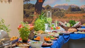 Mesa de buffet con distintos alimentos y un gran árbol al fondo.