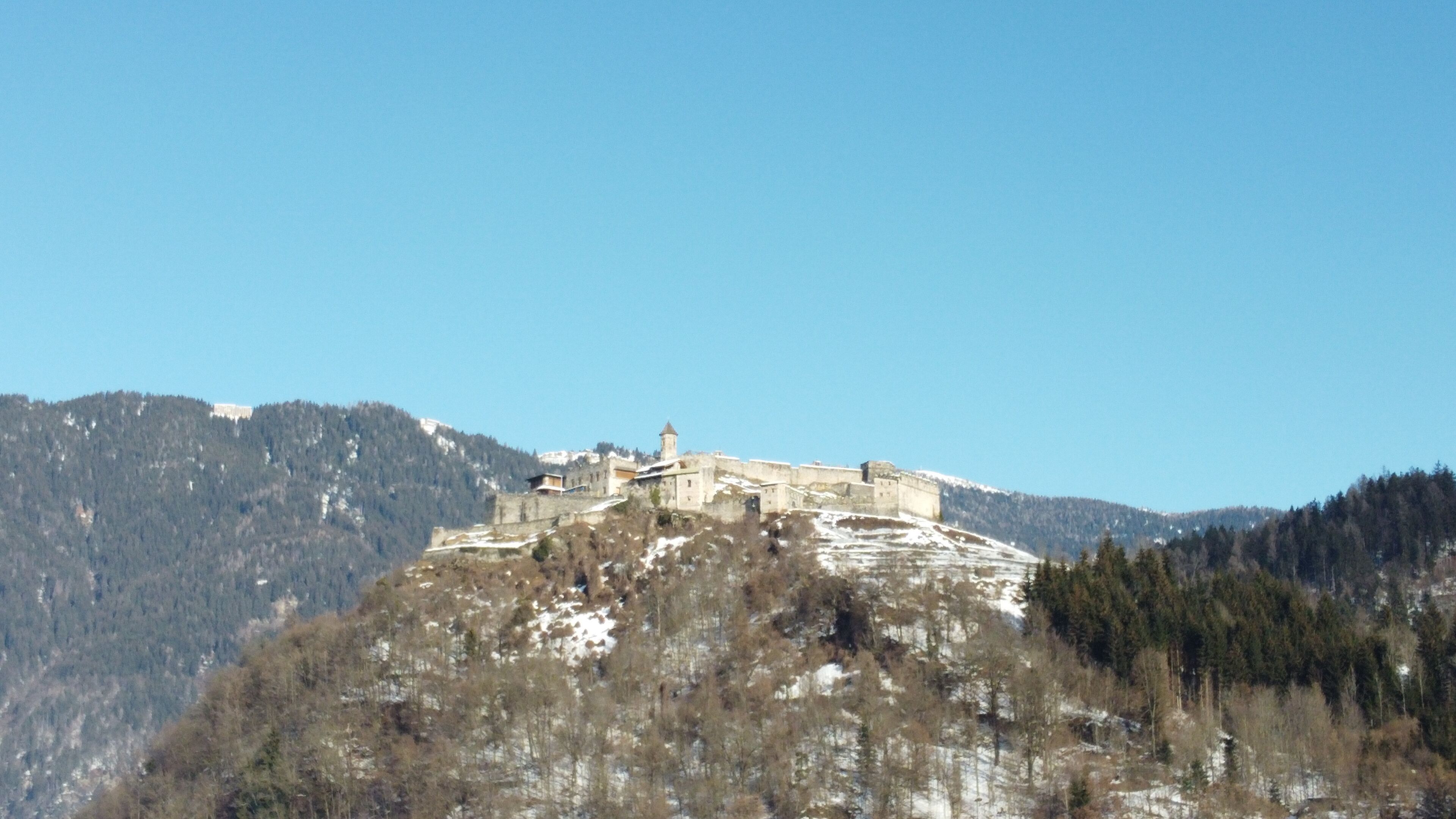 Un castell històric damunt un turó sota un cel serè.