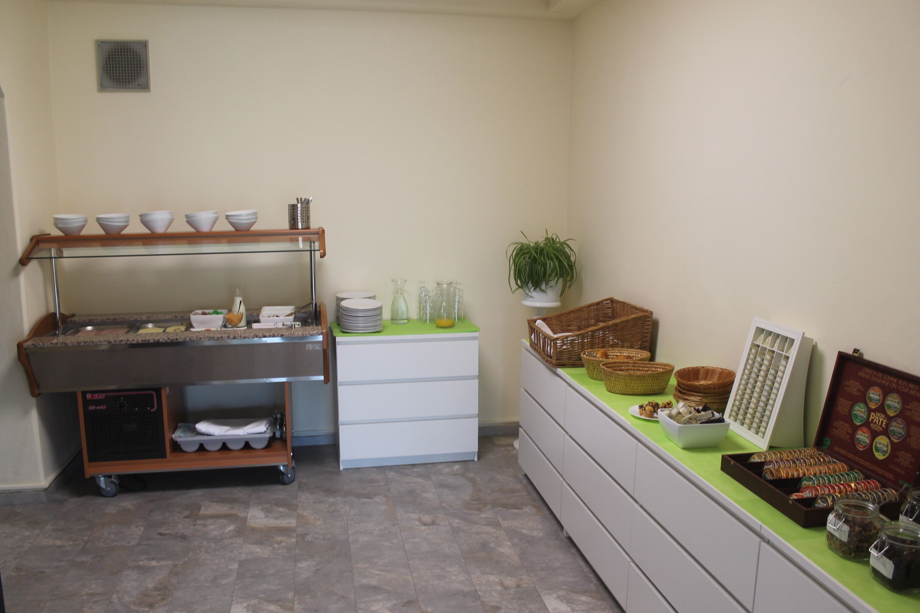 A buffet setup with a glass counter, bowls, baskets, and jars of condiments.