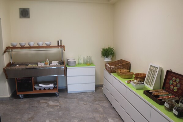 A buffet setup with a glass counter, bowls, baskets, and jars of condiments.