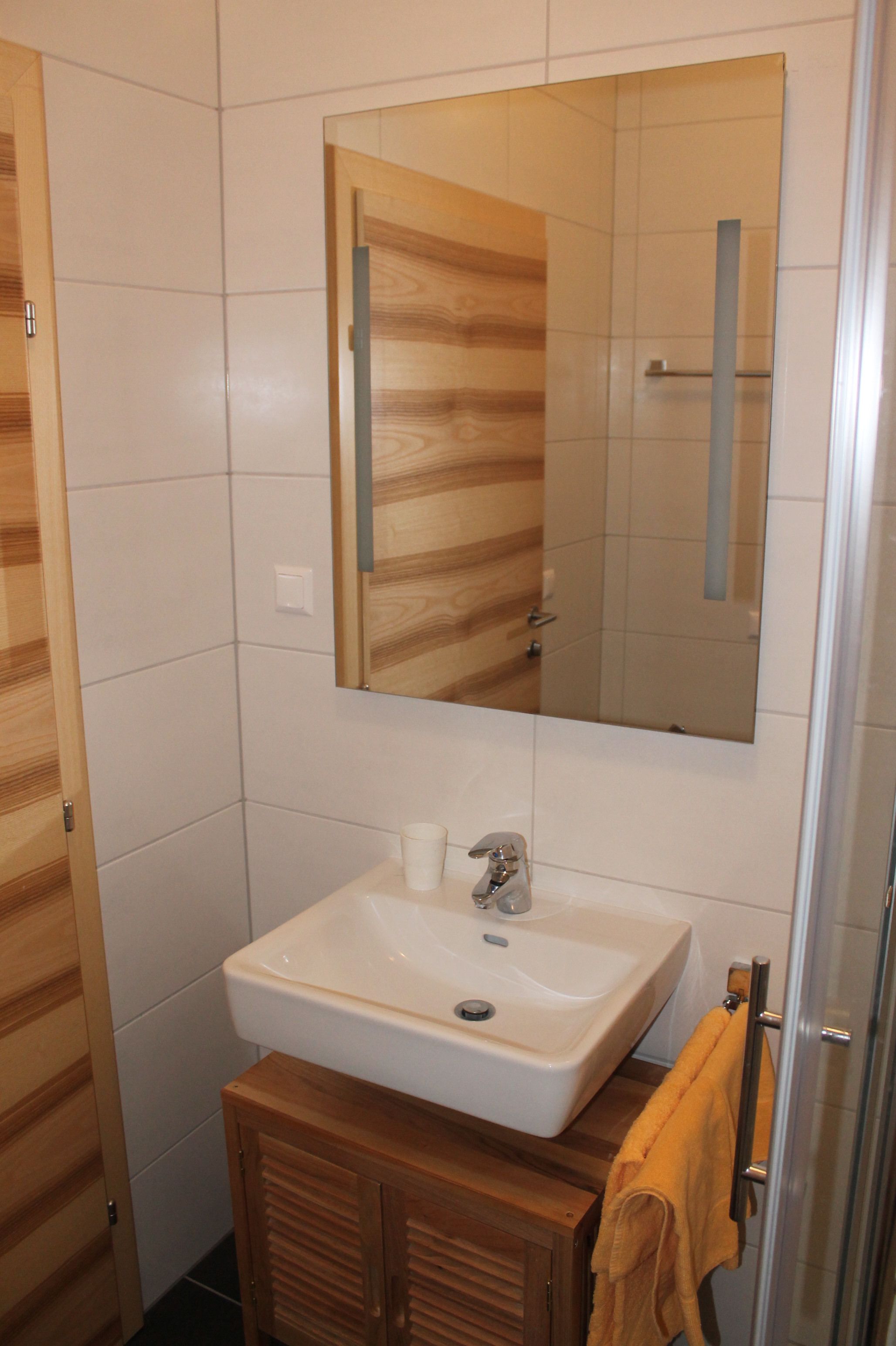 A bathroom with a wooden vanity, a white sink, and a mirror above it.