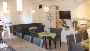 Un espace repas comprenant des tables, des chaises et un téléviseur.