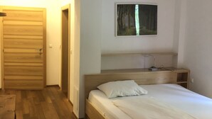Une chambre à coucher avec un lit en bois, une table de chevet, un tableau accroché au mur et une porte en bois.