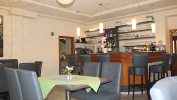 A restaurant with a bar area, multiple tables with chairs, and a decorative ceiling light.