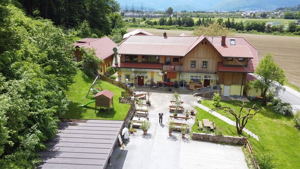 Un grand bâtiment en bois, doté d’un toit recouvert de tuiles rouges, d’un patio abrité et d’une aire de jeux.