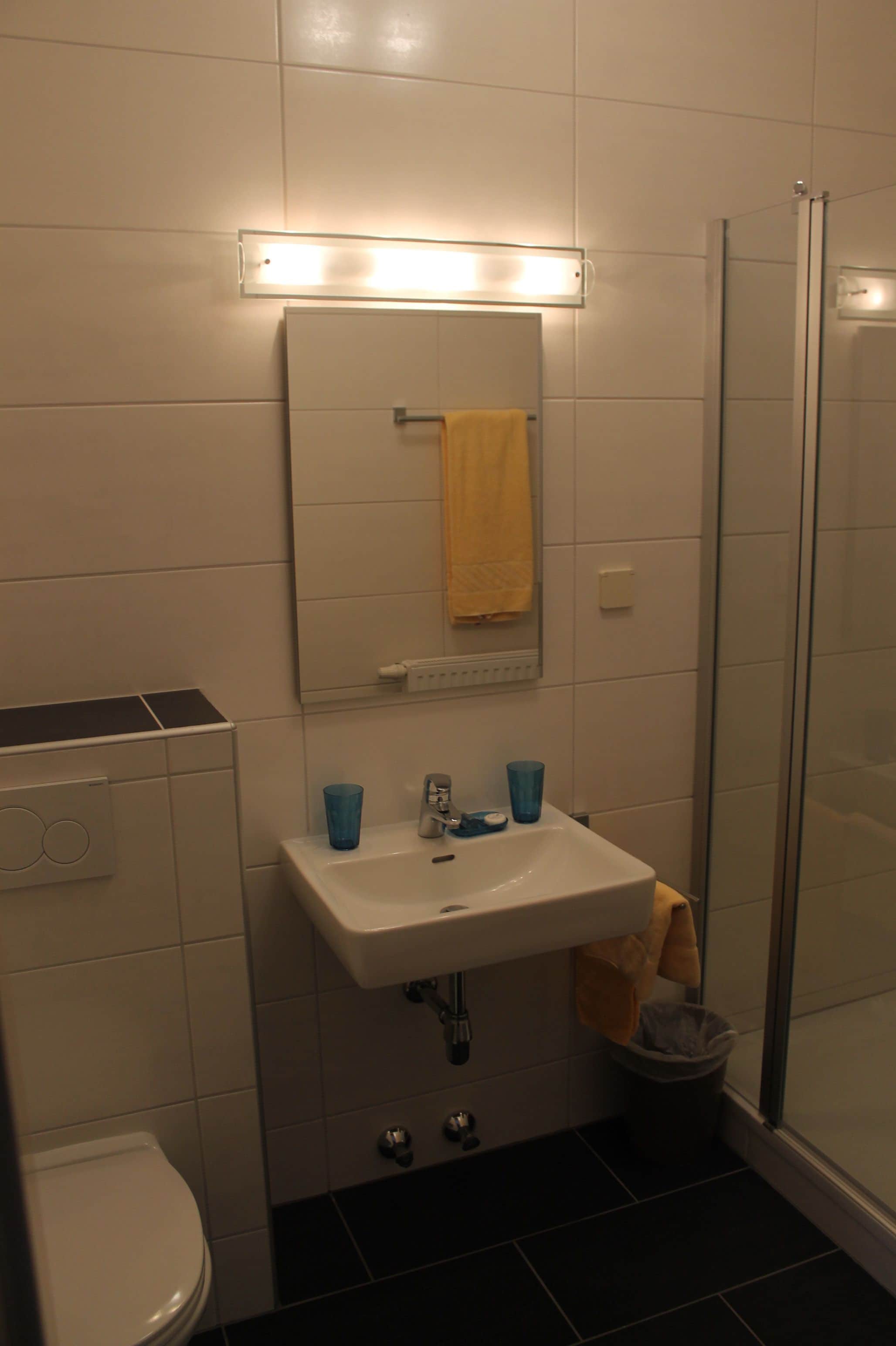 A bathroom with a white sink, mirror, and a glass shower enclosure.