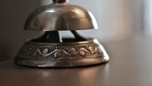 Un objet métallique doté d’un dôme et d’une pompe, qui ressemble probablement à une sonnette de service en chambre, posé sur une surface plane.