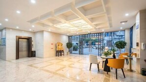 A hotel lobby with a marble floor, a reception desk, and a large window offering a view of the street. - Kaiyue Business Hotel（Ninefang City Shop,Northmen Road ） (KUNSHAN)